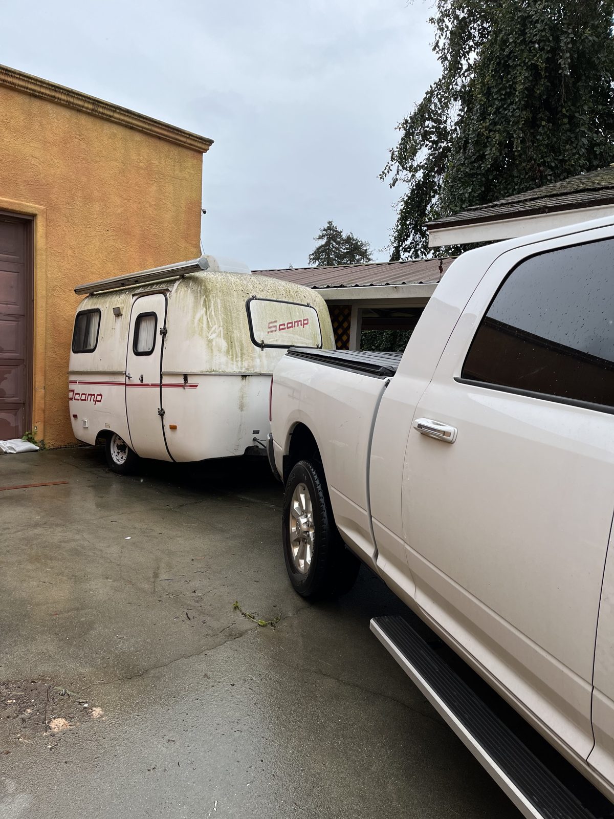 Scamp molded fiberglass compact travel trailer hitched behind a pickup truck